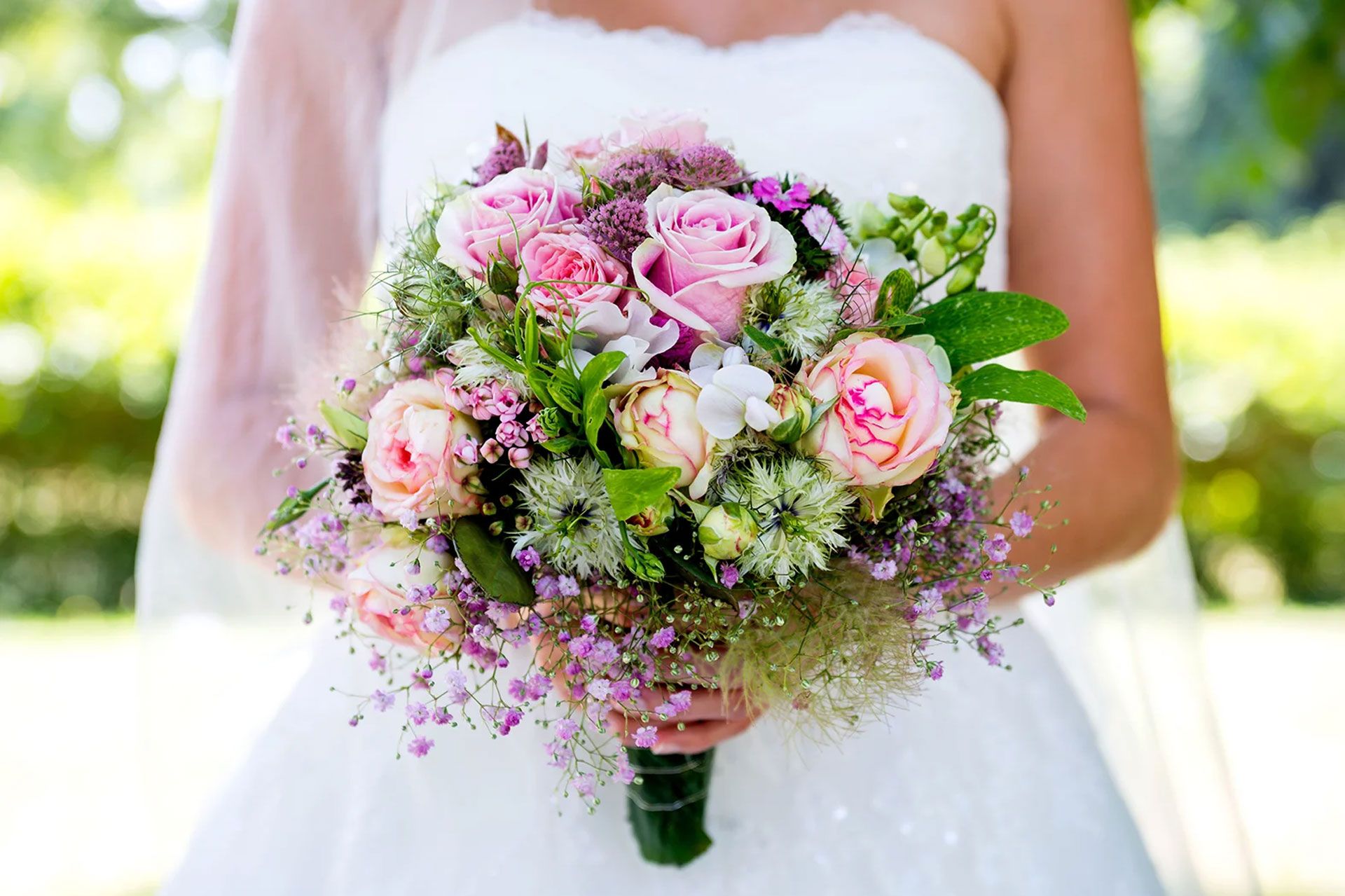 Braut in weißem Kleid hält einen großen Blumenstrauß mit Rosen und anderen Blumen